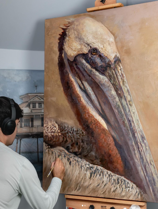 picture of painter Brandon Finnorn working on an oil painting of a pelican on canvas