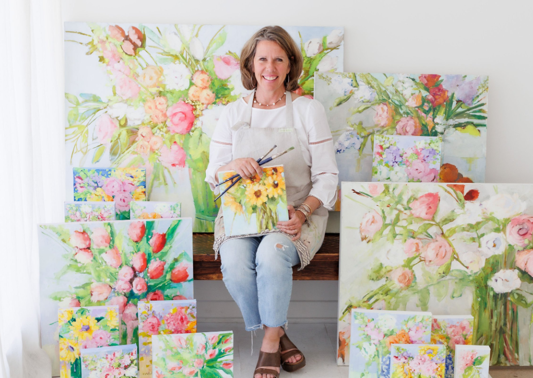 photo of Ruthie Carlson with her paintings
