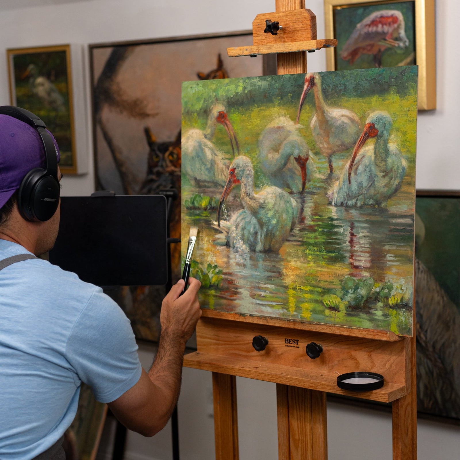 Brandon Finnorn painting a scene of birds on an easel in a studio setting.